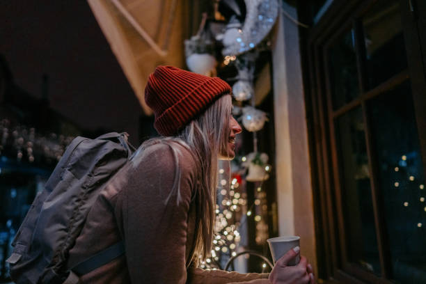 Photo of a young woman drinking hot drink and  walking through the town during the Christmas holidays