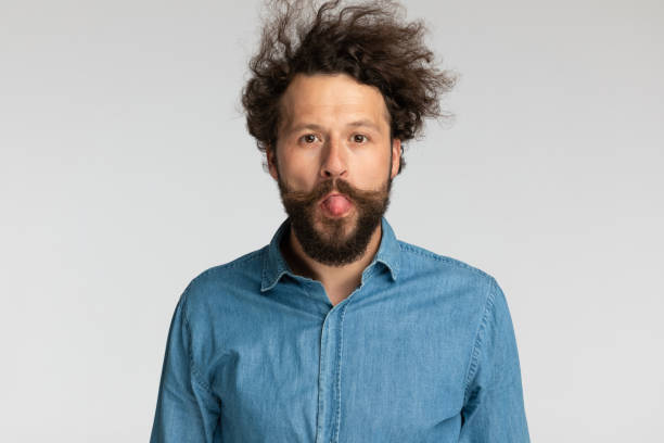 istock goofy young bearded man sticking out tongue and making silly faces 1339043414