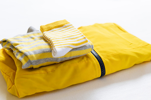 Yellow baby jacket folded neatly together with a set of yellow socks. Yellow dress. Yellow color in everyday life.