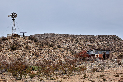 A windmill on a hill above a sheep shearing shed in West Texas
