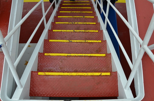 red and yellow metal steps or stairs with railing or hand rail on boat