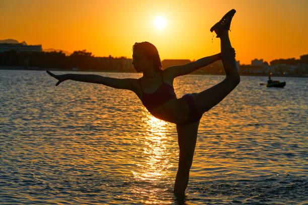 istock Girl gymnastics pose at sunset beach 1339047625