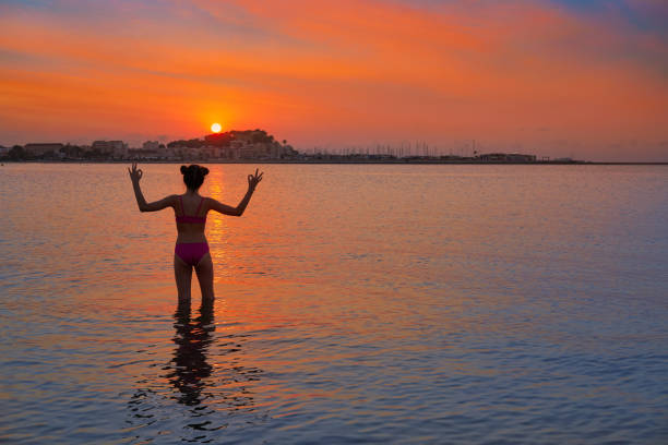 Girl silhouette at beach sunset open arms yoga mudras finger standing