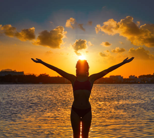 istock Girl silhouette at beach sunset open arms 1339047757