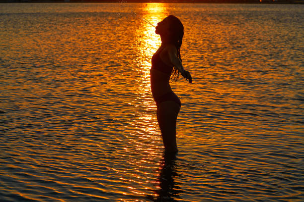 istock Girl silhouette at beach sunset open arms 1339047797