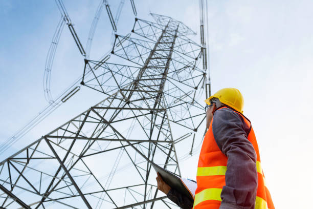 inżynier pracujący na wieży wysokiego napięcia, sprawdź informacje na papierze. - electricity pylon zdjęcia i obrazy z banku zdjęć