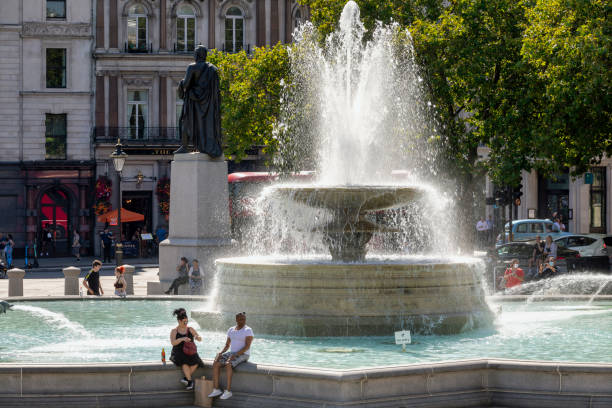 London, UK - April 5 2025: people sit around the fountain in Trafalgar Square on a sunny day