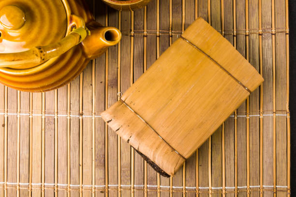 Chinese pressed PU-erh tea in bamboo leaf packaging and tea accessories on a bamboo Mat, close-up