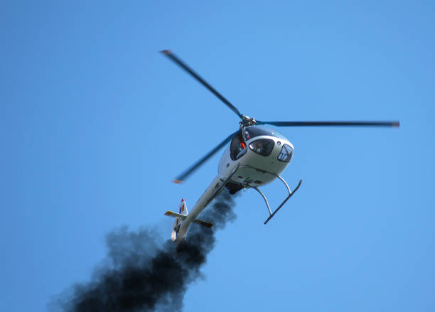 Helicopter with engine problems. Black smoke comes out of the helicopter's engine and the helicopter tries to make an emergency landing. Small helicopter. engine failure stock pictures, royalty-free photos & images