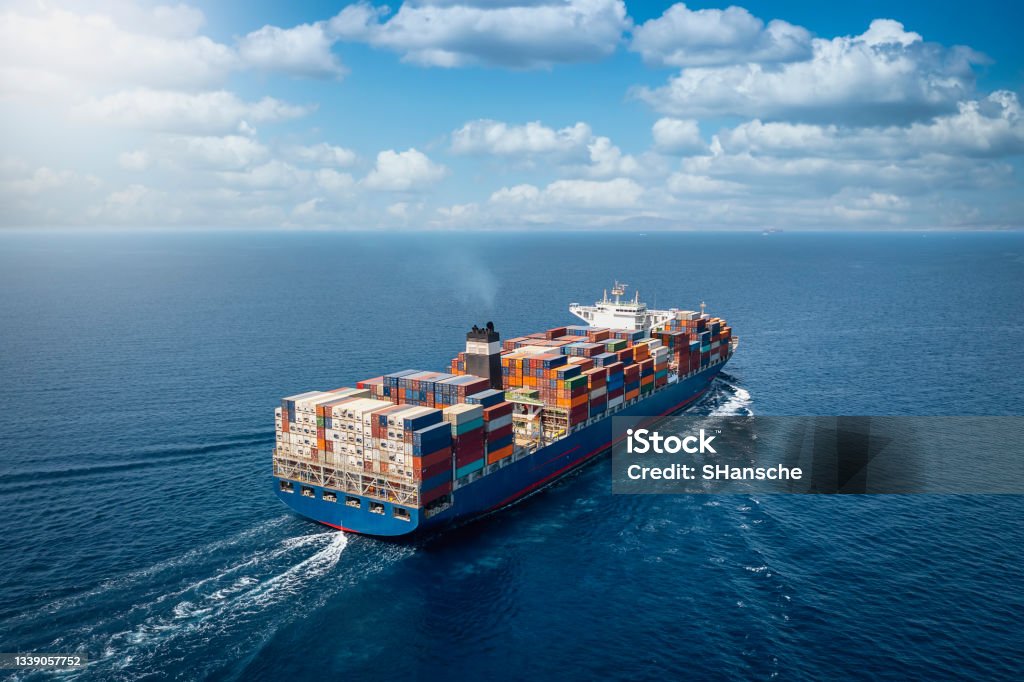 A large container cargo ship in motion A large container cargo ship travels over calm, blue ocean Freight Transportation Stock Photo