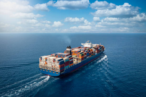A large container cargo ship in motion A large container cargo ship travels over calm, blue ocean shipping stock pictures, royalty-free photos & images