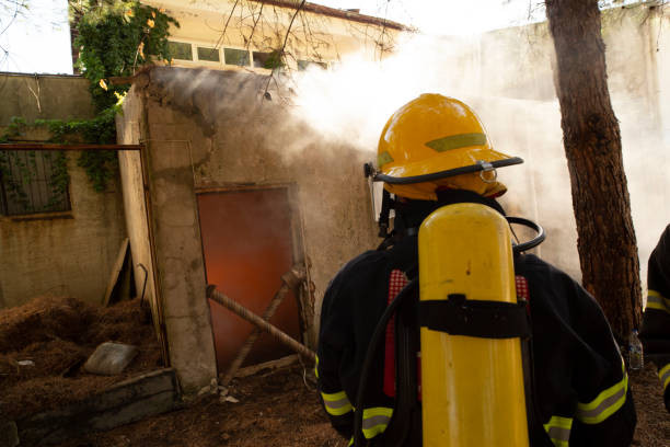 Firefighters in protective gear stand ready in front of a building, responding to an emergency that may require Fire Damage Restoration services afterward.