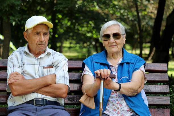 istock Elderly couple sitting with walking sticks on a bench 1339066275