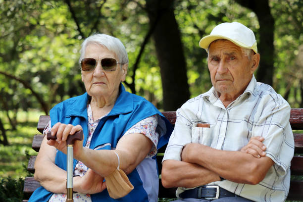 istock Elderly couple sitting with walking sticks on a bench 1339066360