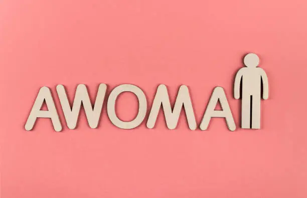Awoman. Wooden figurines on pink paper background. Note about the awoman. New normal concept.