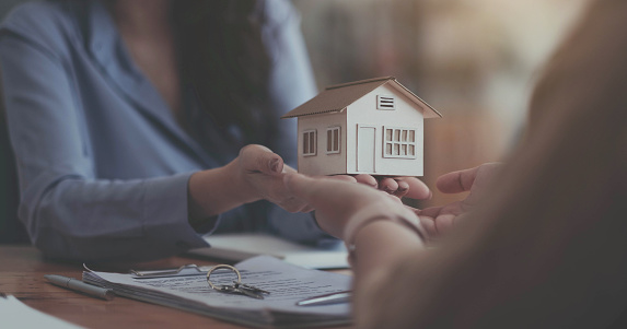 Estate agent giving house keys to customer after contract signature