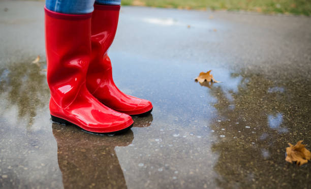 Rubber boots are jumping into a big puddle with splash.