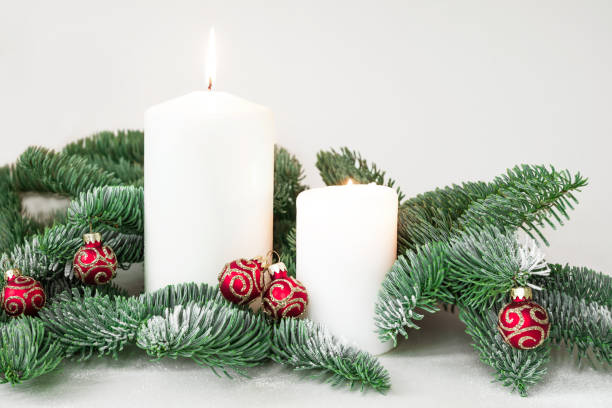 istock Christmas composition with lighted candles and glittering red baubles surrounded with fir branches on white background 1339072669