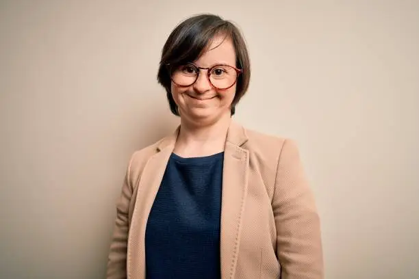 Photo of Young down syndrome business woman wearing glasses standing over isolated background with a happy and cool smile on face. Lucky person.