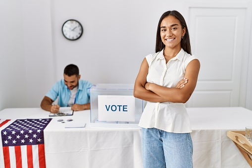Young american voter woman smiling happy standing with arms crossed gesture at electoral colleage.