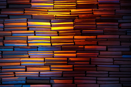 stack of old paper books, illuminated by the light of a lamp. Background and texture. Hobby, leisure, leisure reading and study concept