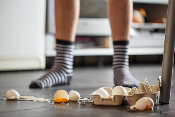 Broken eggs - accident at kitchen, mess. Legs on background Broken eggs - accident at kitchen, mess. Legs on background careless stock pictures, royalty-free photos & images