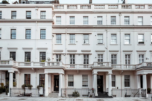 Long row of elegant white stucco townhouses in an expensive London neighborhood.
