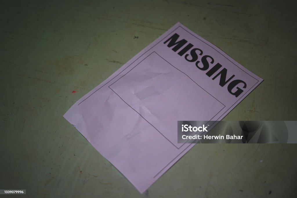The paper that said Missing lay on the wooden table. Missing person search concept Missing Persons Stock Photo