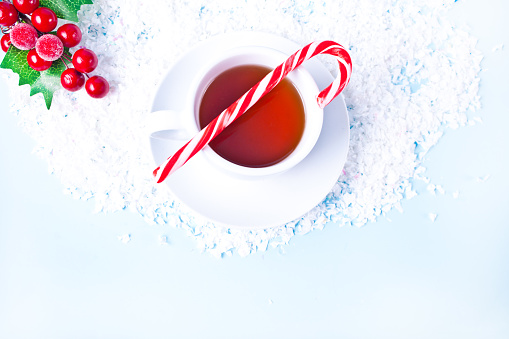 Hot winter tea with Christmas decoration, sweets and candy cane. Top view.