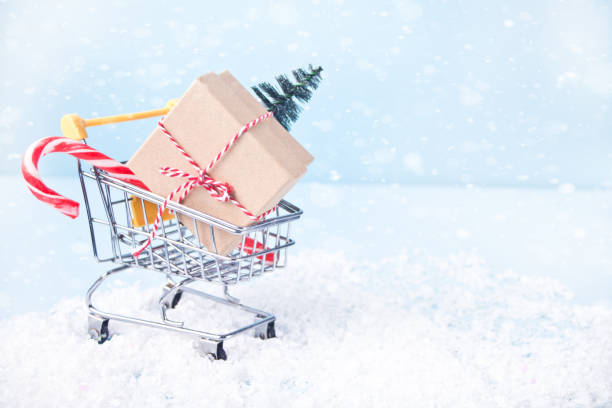 Christmas composition with shopping cart and gift box, fir trees stock photo