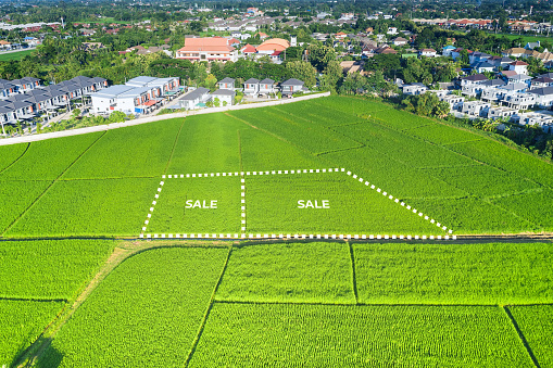 Land for sale in aerial view. Consist of landscape of green field or agriculture farm, residential or house building in village. That real estate or property and plot of land lot for trade business i.e. owned, sale, development, rent, buy or purchase in Chiang Mai of Thailand.