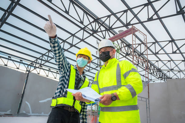 civil engineer inspect structure at construction site against blueprint, building inspectors jointly inspect the building structure with civil engineer. civil engineer hold blueprint inspect building. - civil building imagens e fotografias de stock