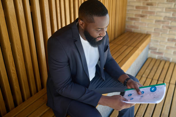 istock A businessman in a suit sitting on a bench with documents for analyzing in hands 1339085242