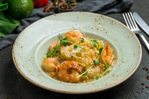 Fettuccine with shrimp on creamy sause on dark stone table