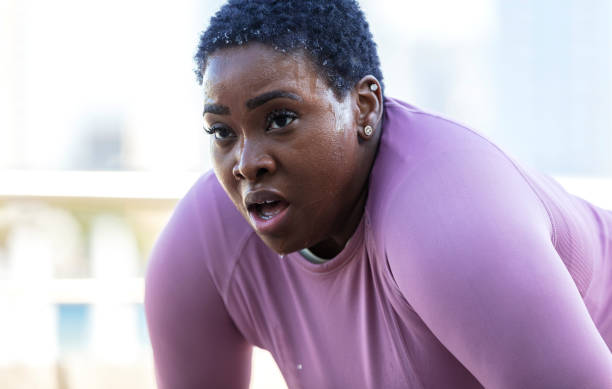 femme afro-américaine transpirant après une séance d’entraînement difficile - se courber en avant photos et images de collection