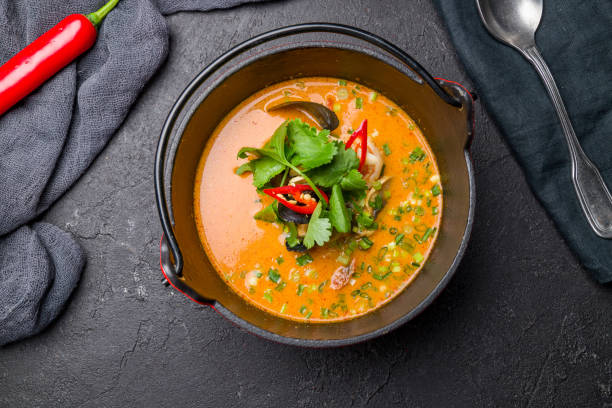istock Tom Yam soup on cast iron bowl with seafood on black stone table top view 1339086728