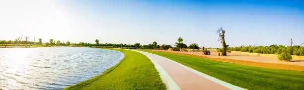 Photo of Panoramic view of a lake and grass walkway or track. Love lake Dubai United Arab Emirates.