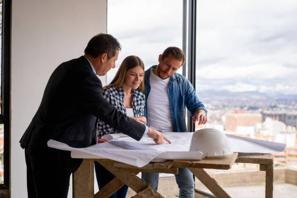 istock Real estate developer showing the blueprints of a house to a couple at the construction site 1339089727