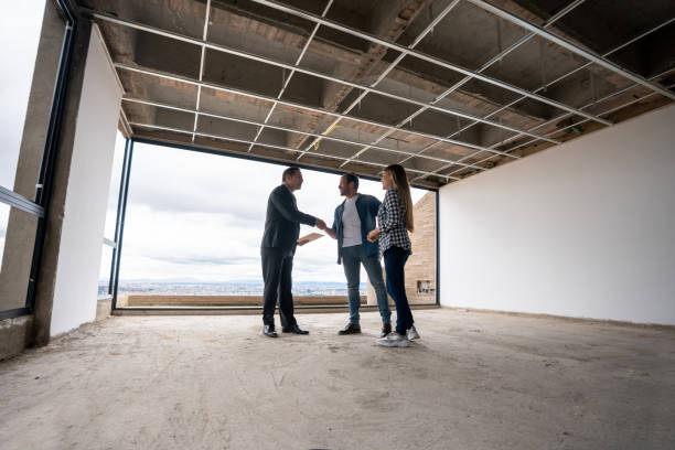 agente de bienes raíces que muestra una casa en construcción a una pareja y los saluda con un apretón de manos - construction construction site handshake built structure fotografías e imágenes de stock