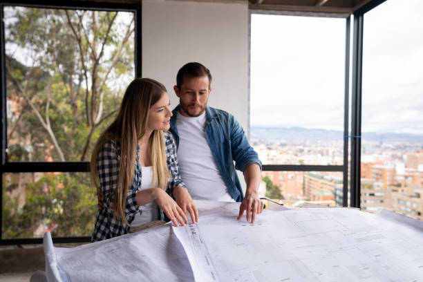 istock Couple remodeling their house and looking at the blueprints at a construction site 1339089804