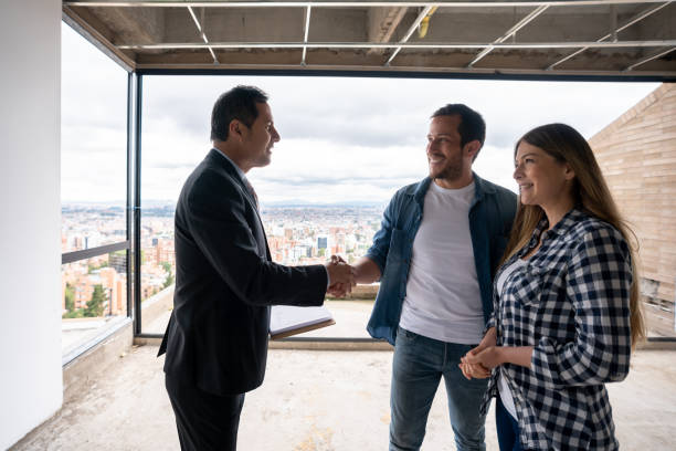 istock Architect greeting a couple with a handshake while showing them a house under construction 1339089808