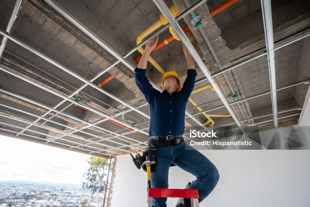 Building contractor checking the pipes at a construction site Latin American building contractor checking the pipes at a construction site - housing develpment concepts Plumber Stock Photo