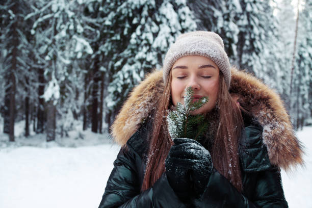 A happy smiling woman in warm clothes holds a pine twig in her hand stock photo