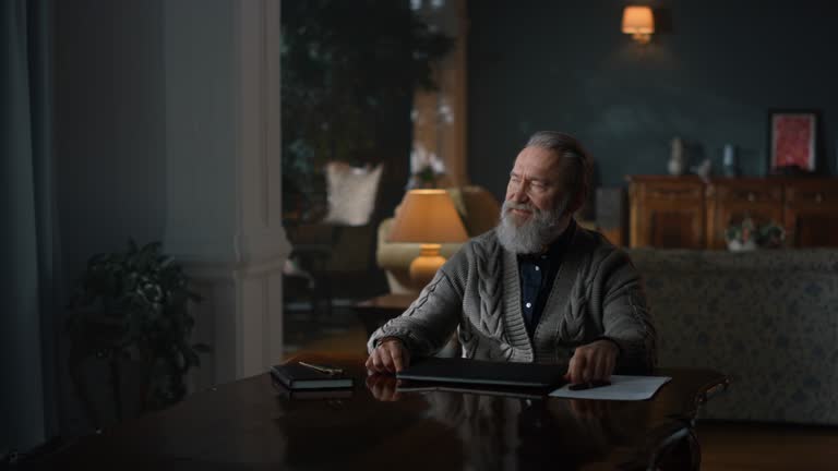 Senior business man finishing work on laptop computer in vintage cabinet