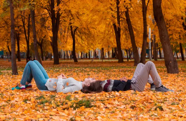 Young couple lying on leaves in the fall park. Mixed race couple