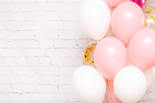 Large bunch of pink and white birthday balloons isolated brick wall background.Card invitation to birthday party. Place for text, copy space, mock up