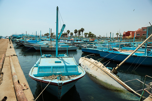 Hurghada, Egypt - August 26, 2021: Fish Market port full of trash and poor hygiene. All fishing boats are painted light blue.