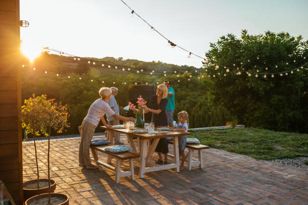 istock Dinner is preparing joint forces. Female members setting dining table in the backyard and male members barbecuing beside them. 1339113658