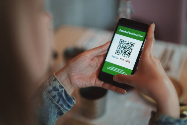 istock Woman checking smartphone app with certificate of immunization in restaurant. Status is invalid. 1339116391