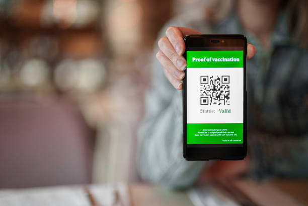 istock Woman showing smartphone app with certificate of immunization in restaurant. Status is valid. 1339116450